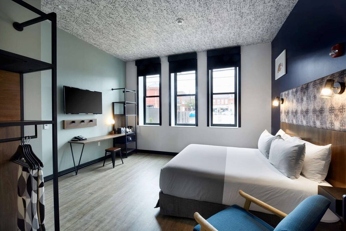 Ein modernes Hotelzimmer mit einem großen Bett, einem Schreibtisch und einem Fernseher.