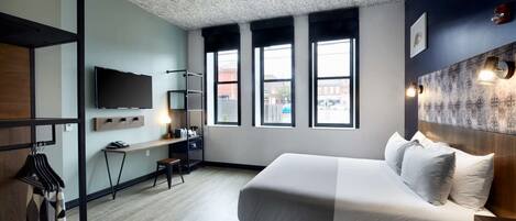 Una habitación de hotel moderna con una cama grande, un escritorio y un televisor.