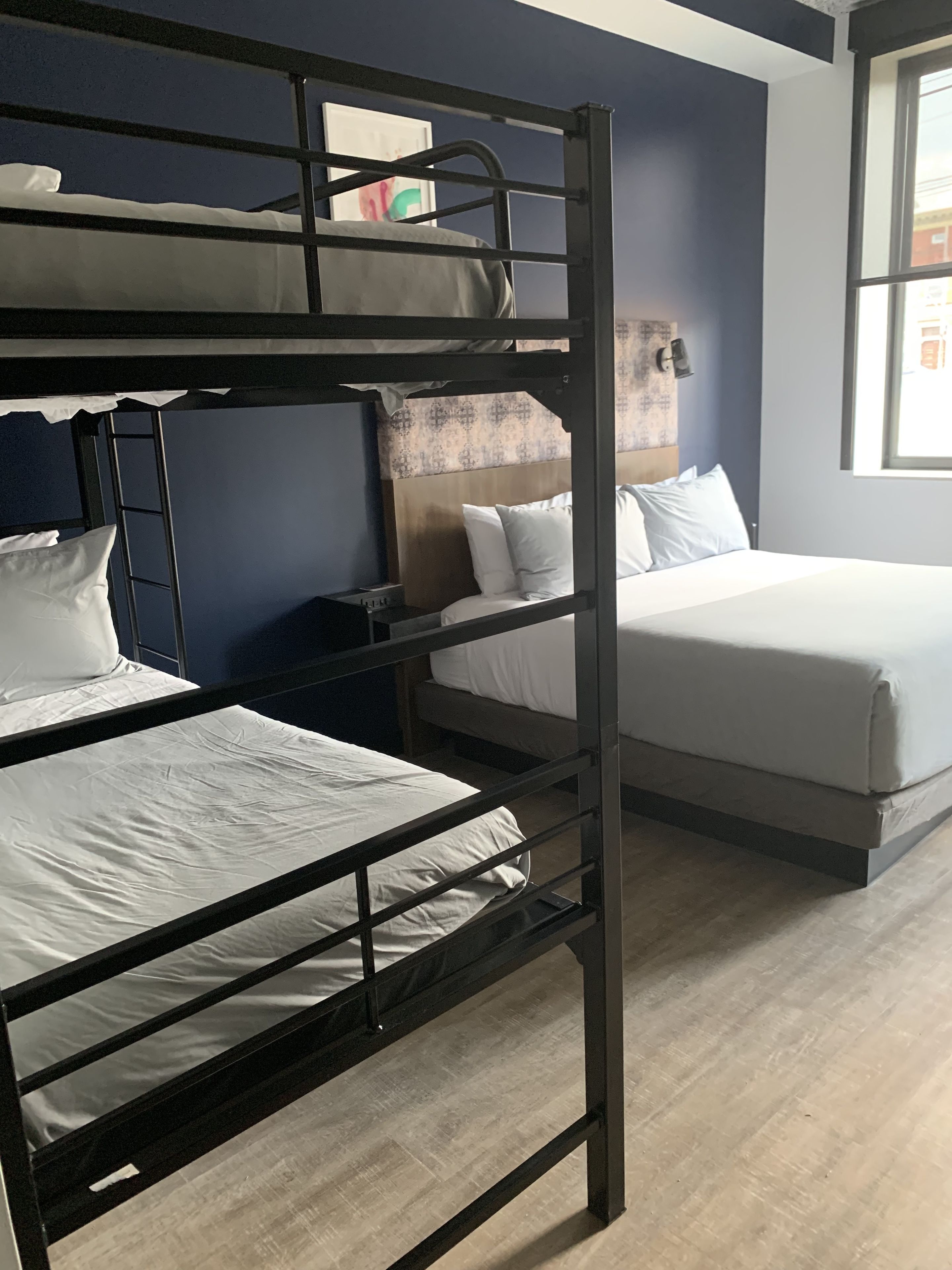 A bunk bed room with a ladder, a desk, and a bed with white bedding.
