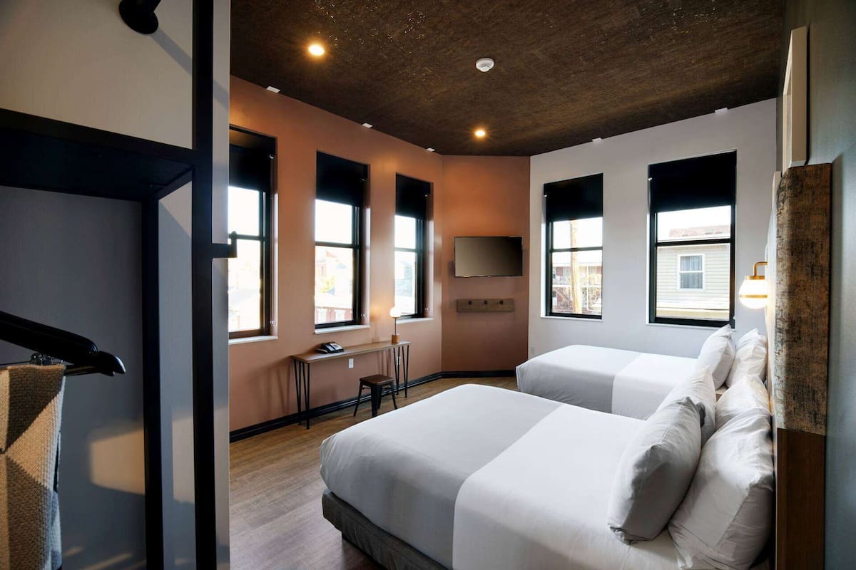 Ein modernes Hotelzimmer mit zwei Betten, einem Schreibtisch und einem Fernseher.