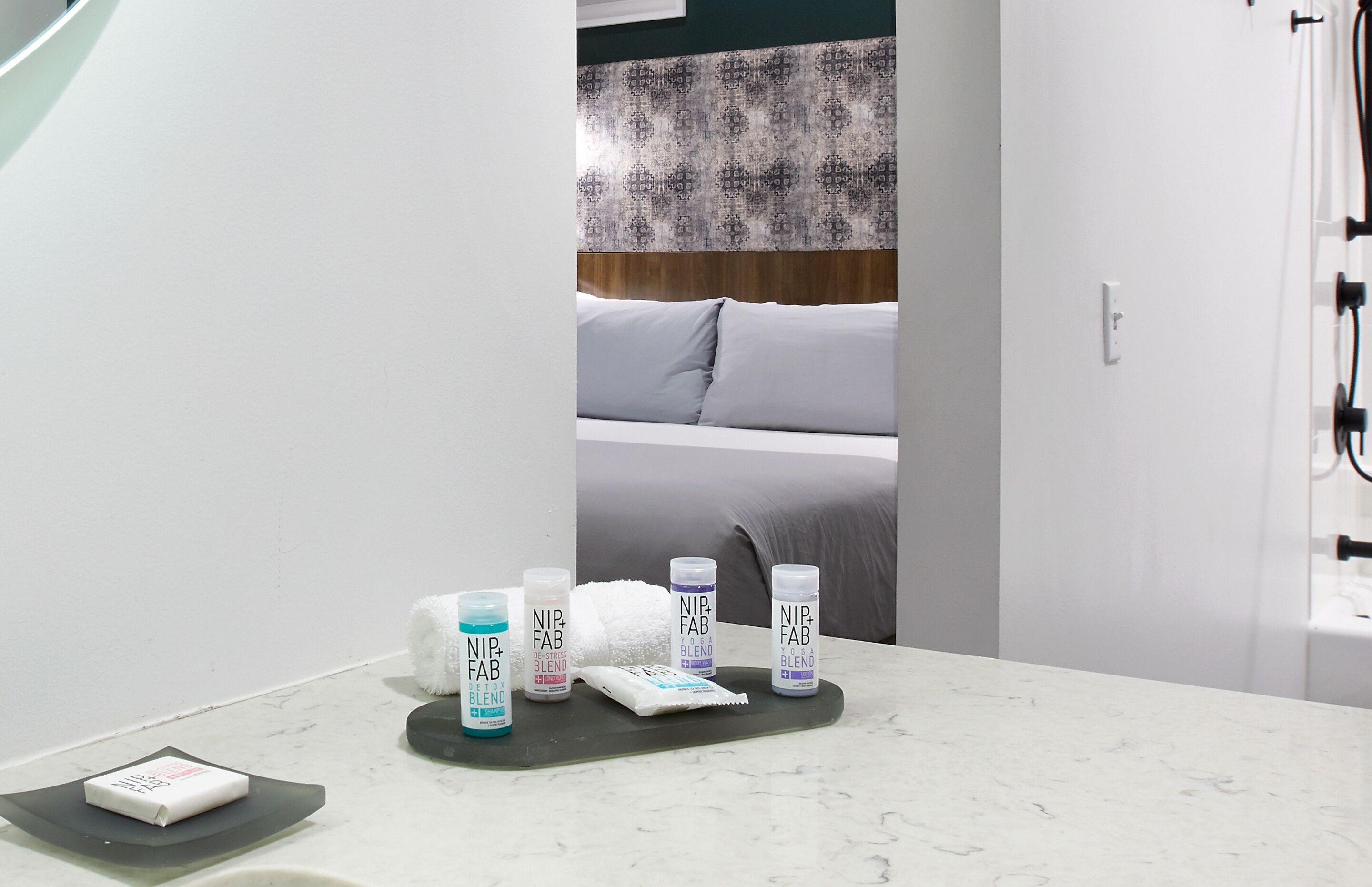 A bathroom with a white countertop, a towel, and NIP-FAB blend toiletries.