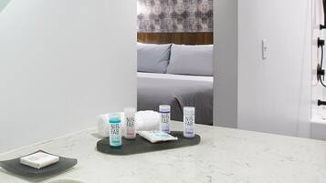 A bathroom with a white countertop, a towel, and NIP-FAB blend toiletries.