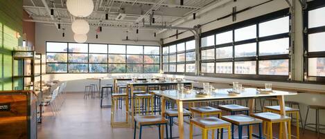 A spacious dining area with high ceilings, large windows, and a view of the cityscape.