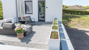 Eine moderne Terrassenanlage mit einer Couch, Stühlen und einem Esstisch.