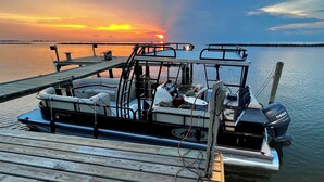 A boat docked at a pier with a sunset in the background. - My ReWard Sunset House has a 450’ pier with boat slips, crabbing, fishing, swim (Grand Isle)
