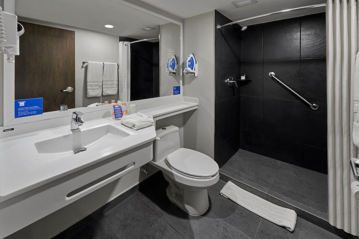 Un baño moderno con un lavamanos blanco, inodoro y zona de ducha.