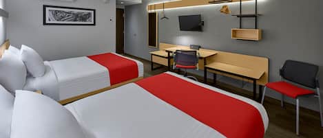 Habitación de hotel con dos camas, un escritorio, una silla, un televisor y un estante.
