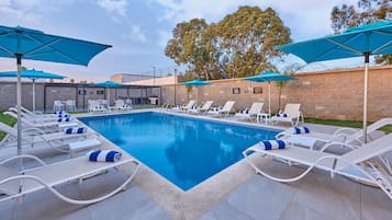 Una piscina al aire libre, sillones reclinables de piscina