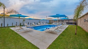 Una piscina al aire libre, sillones reclinables de piscina