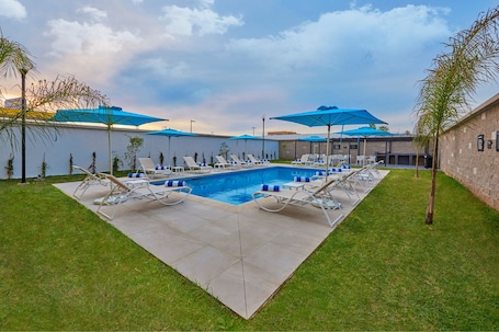 Una piscina al aire libre, sillones reclinables de piscina