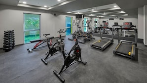 Uma academia moderna com bicicletas ergométricas, esteiras e uma estrutura para pesos.
