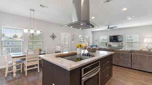 Una cocina moderna con una isla central, horno empotrado y una zona de comedor con mesa y sillas.