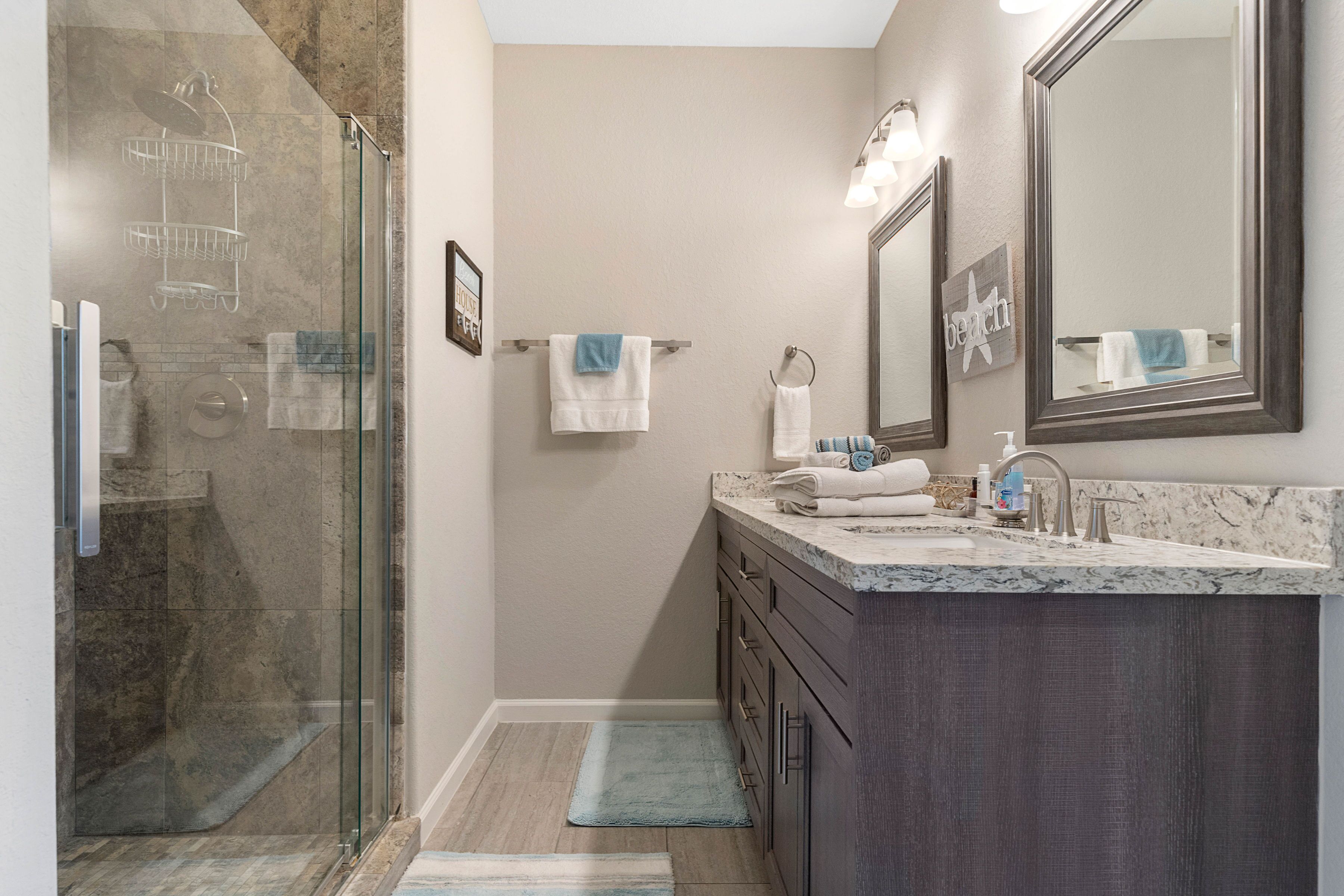 Une salle de bain moderne avec une douche à parois de verre, un lavabo en marbre et un grand miroir.