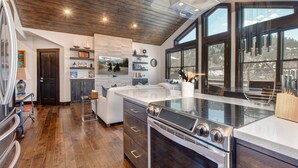 Uma cozinha moderna com uma ilha grande, eletrodomésticos de aço inoxidável e vista para uma paisagem nevada através de grandes janelas.