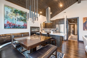Une cuisine moderne dotée d’un grand îlot central, de planchers en bois foncé et d’un luminaire suspendu.
