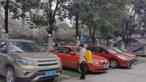 A parking area with a beige SUV and a red car.