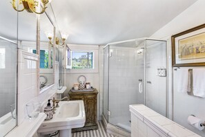 A modern bathroom with a large mirror, a sink, a vanity, a shower, and a glass-enclosed shower stall. - The Bissell House Bed and Breakfast (South Pasadena)