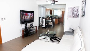 A modern living room with a flat-screen TV, a glass coffee table, and a white sofa. - Exclusive Penthouse with Hot Tub (Santiago de los Caballeros)