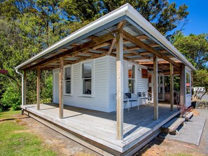 Une petite cabane à un seul étage, dotée d’une terrasse en bois et d’un porche abrité.