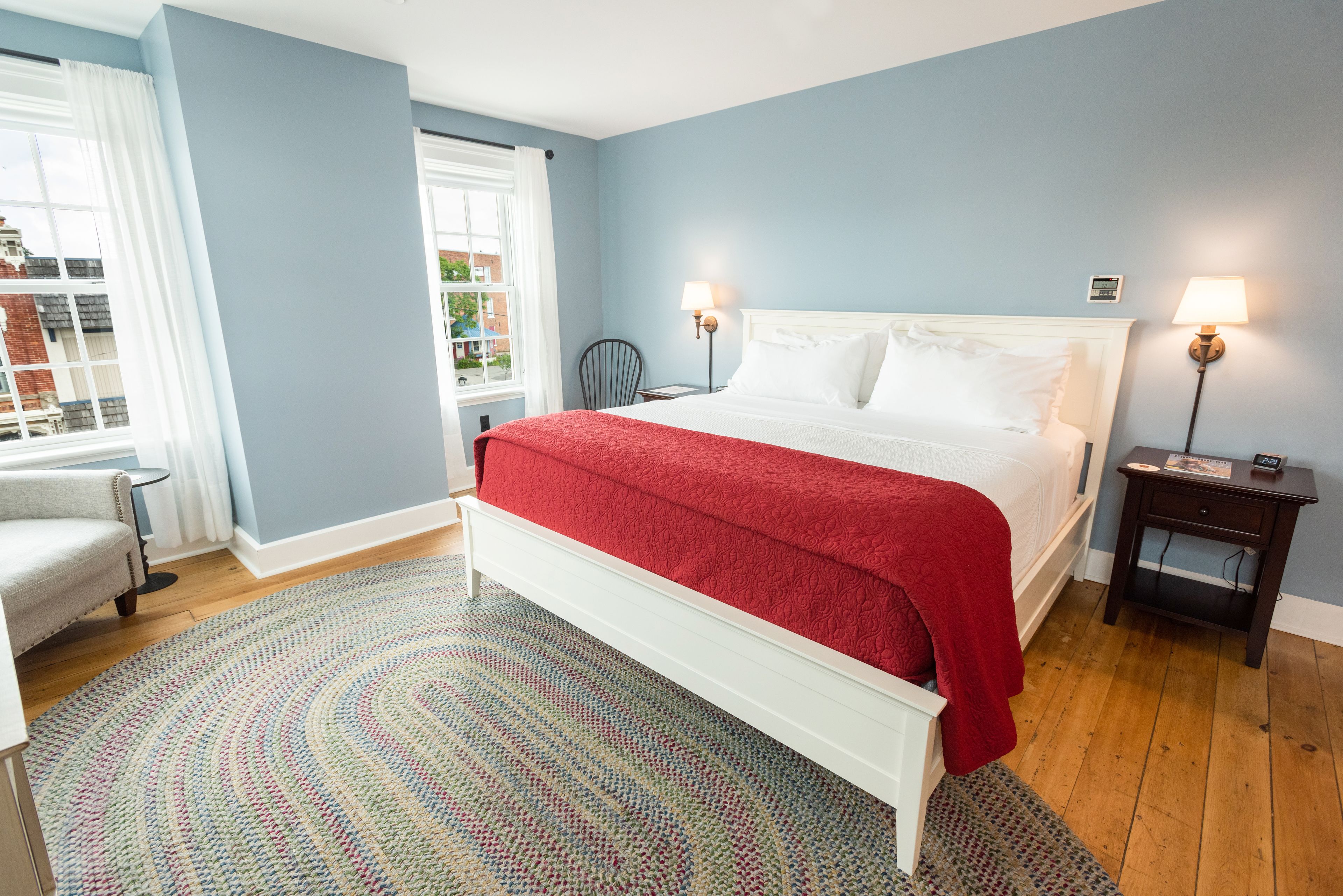 A bedroom with a large bed, a chair, a small table, and a lamp.