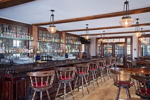 A bar area with wooden chairs and a bar counter stocked with liquor bottles and glasses. - The Cadillac House Lexington, Tapestry Collection by Hilton (Lexington)
