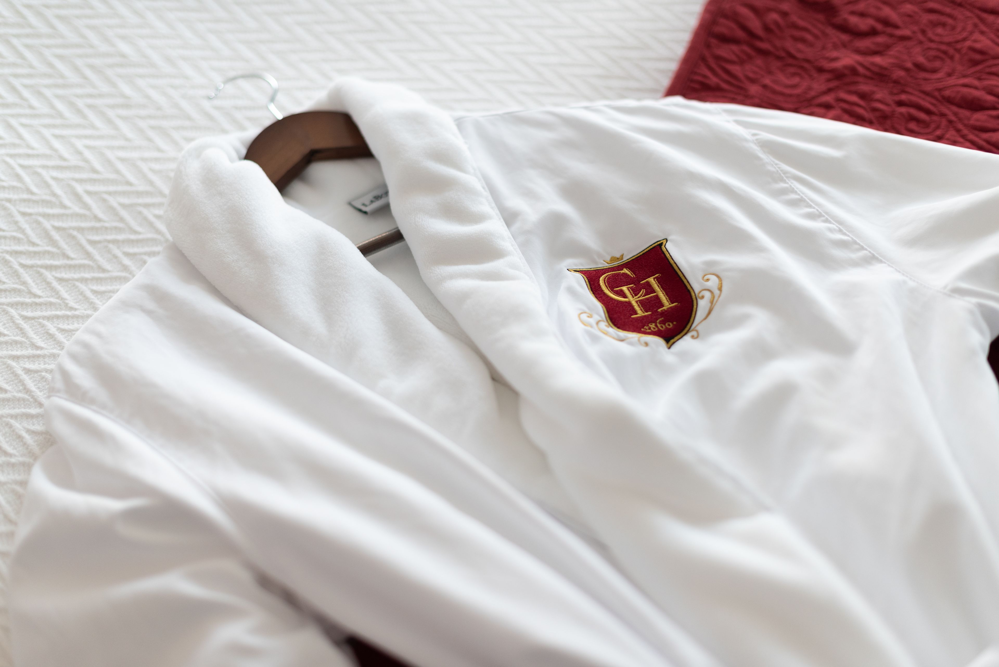 A white robe with a crest on a bed.