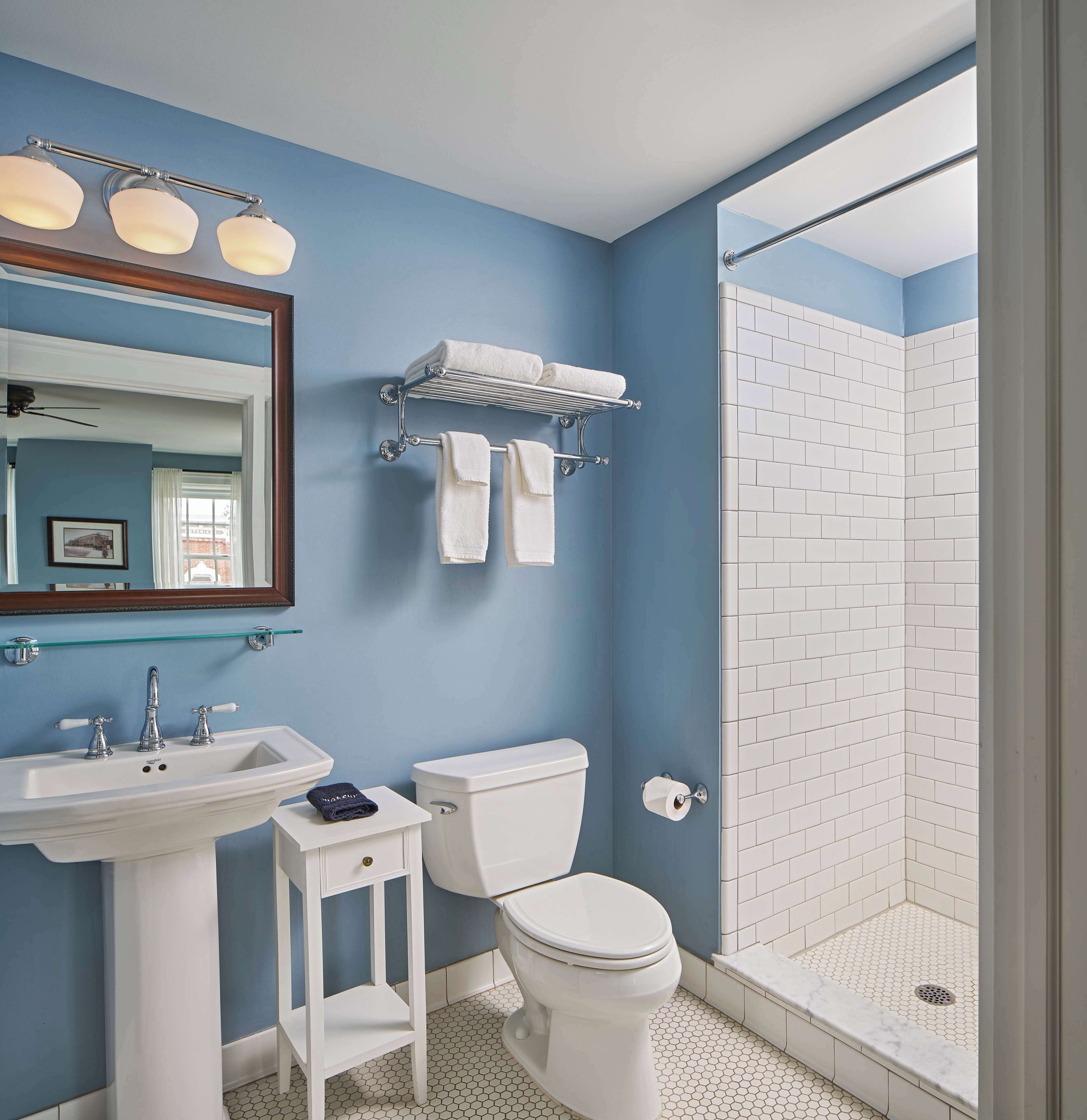 Une salle de bain avec un mur bleu, un lavabo blanc, des toilettes et une douche.