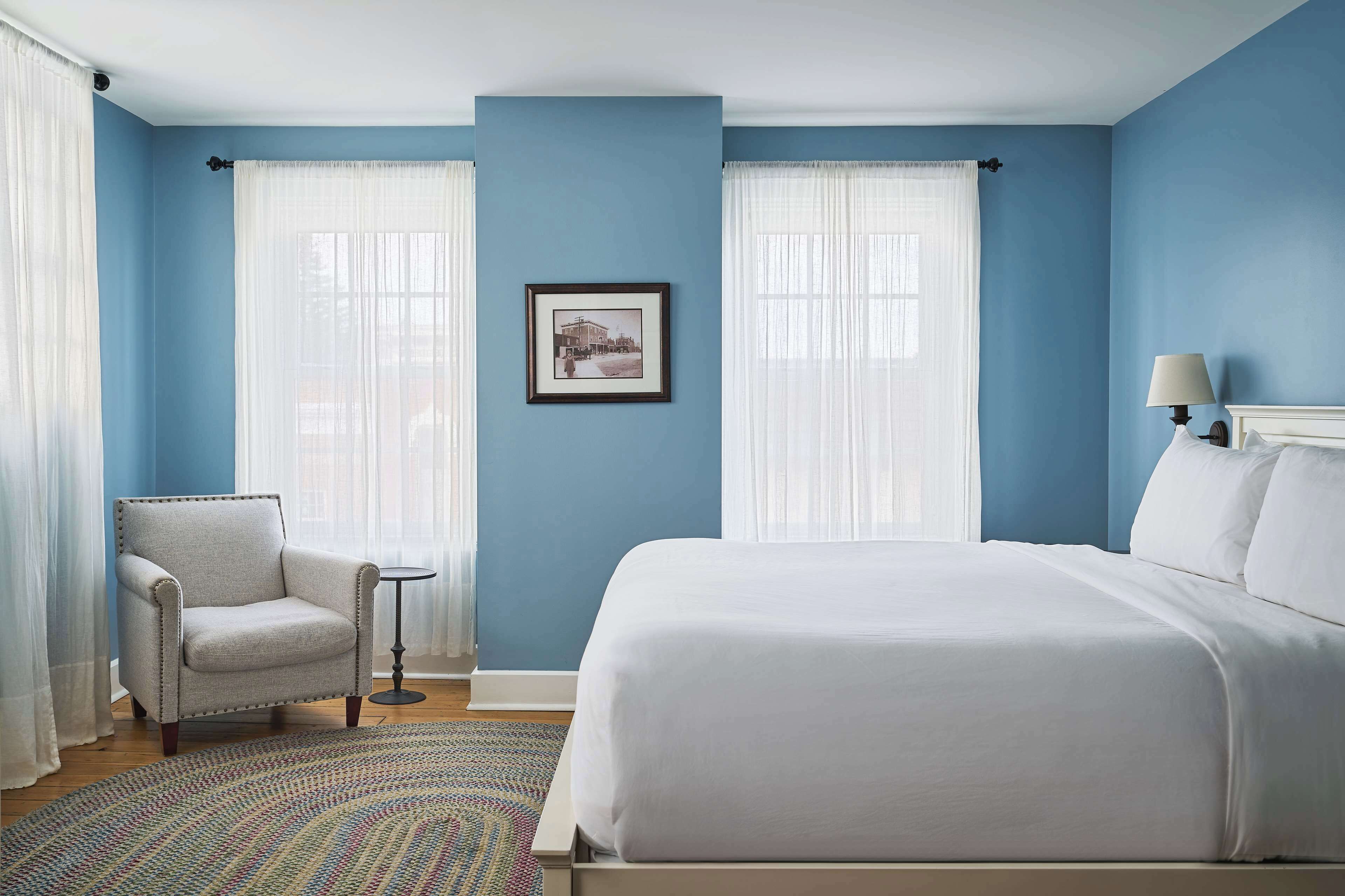 Une chambre avec un grand lit, une chaise et une petite table.