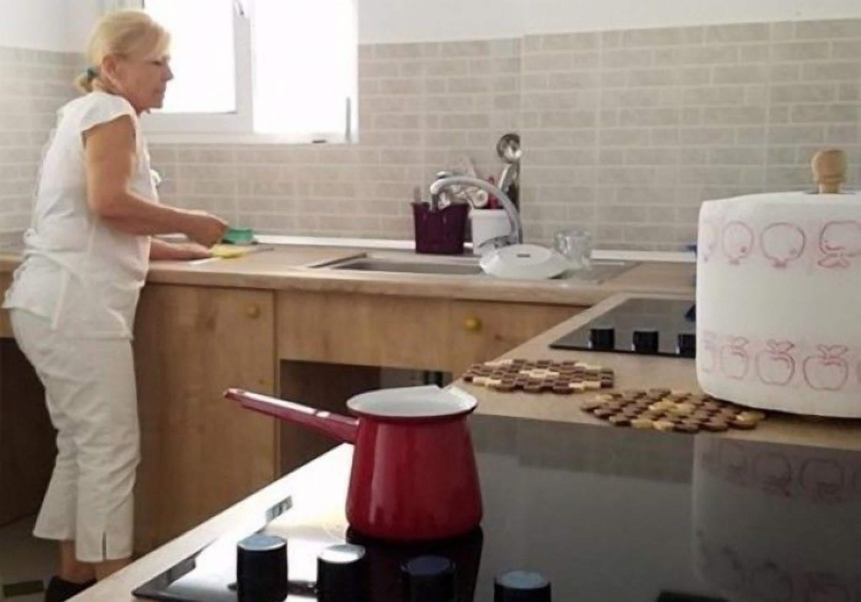 A kitchen with a sink, a red kettle, and a cake on the counter.