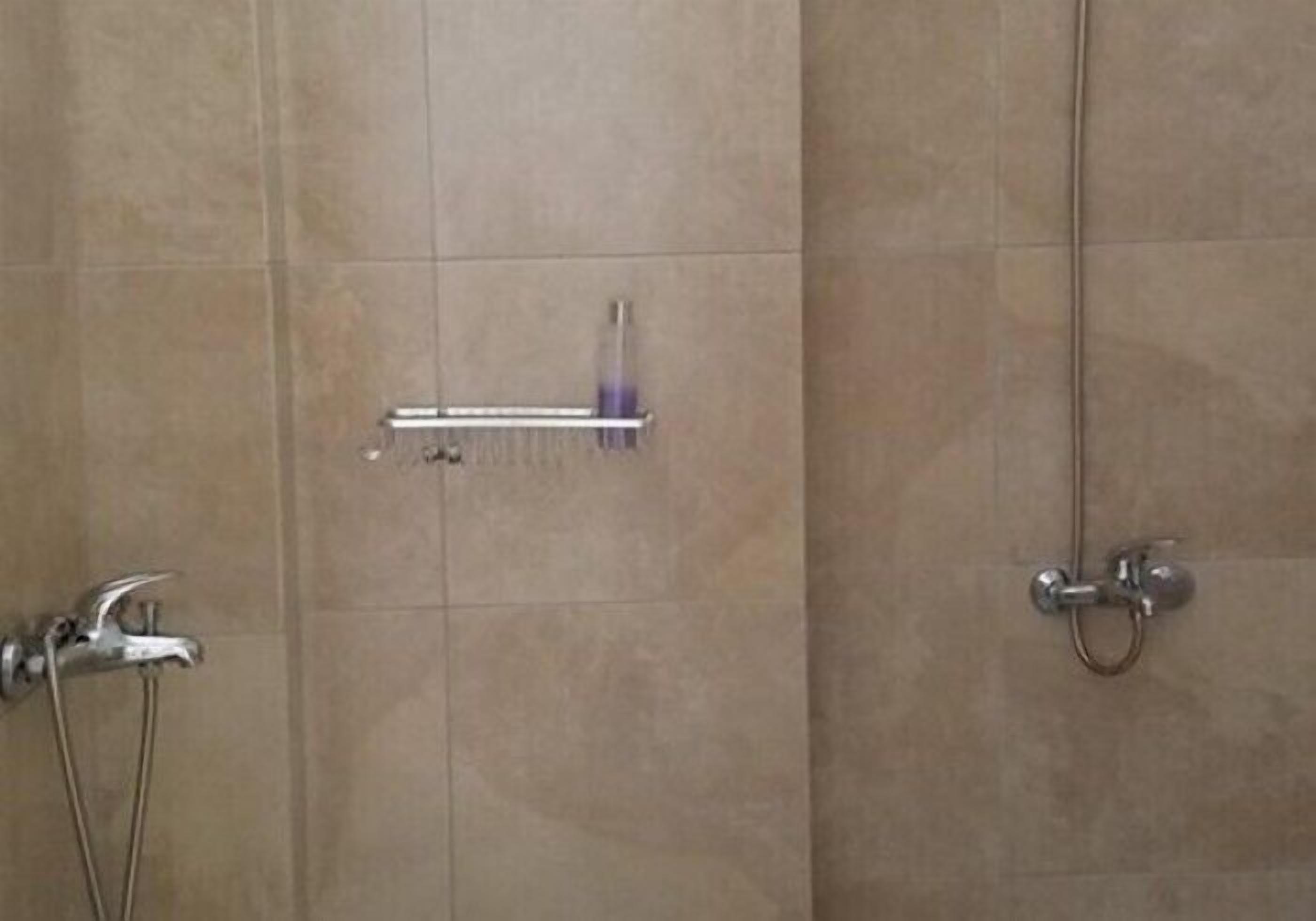 A bathroom with a shower, a towel rack, and a toilet.