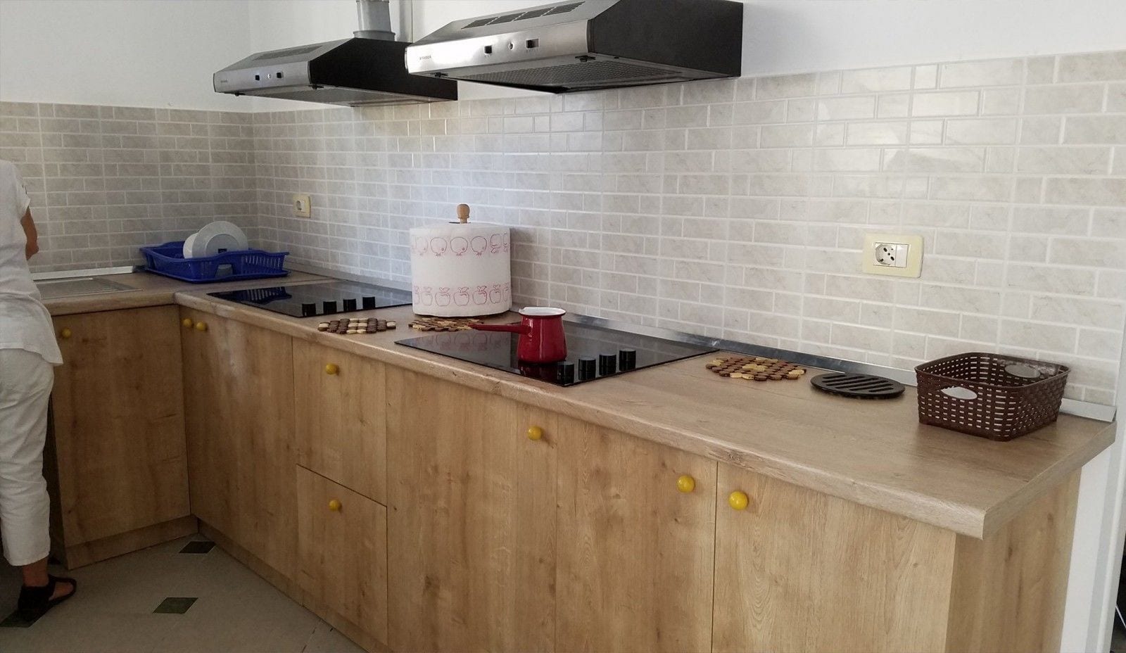 Een keuken met een houten aanrecht, een gasfornuis en een afzuigkap. Er staan diverse keukengerei en een blauwe mand op het aanrecht.