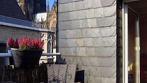 A modern building with stone walls, a wooden deck, a table with chairs, and a view of a gothic church.