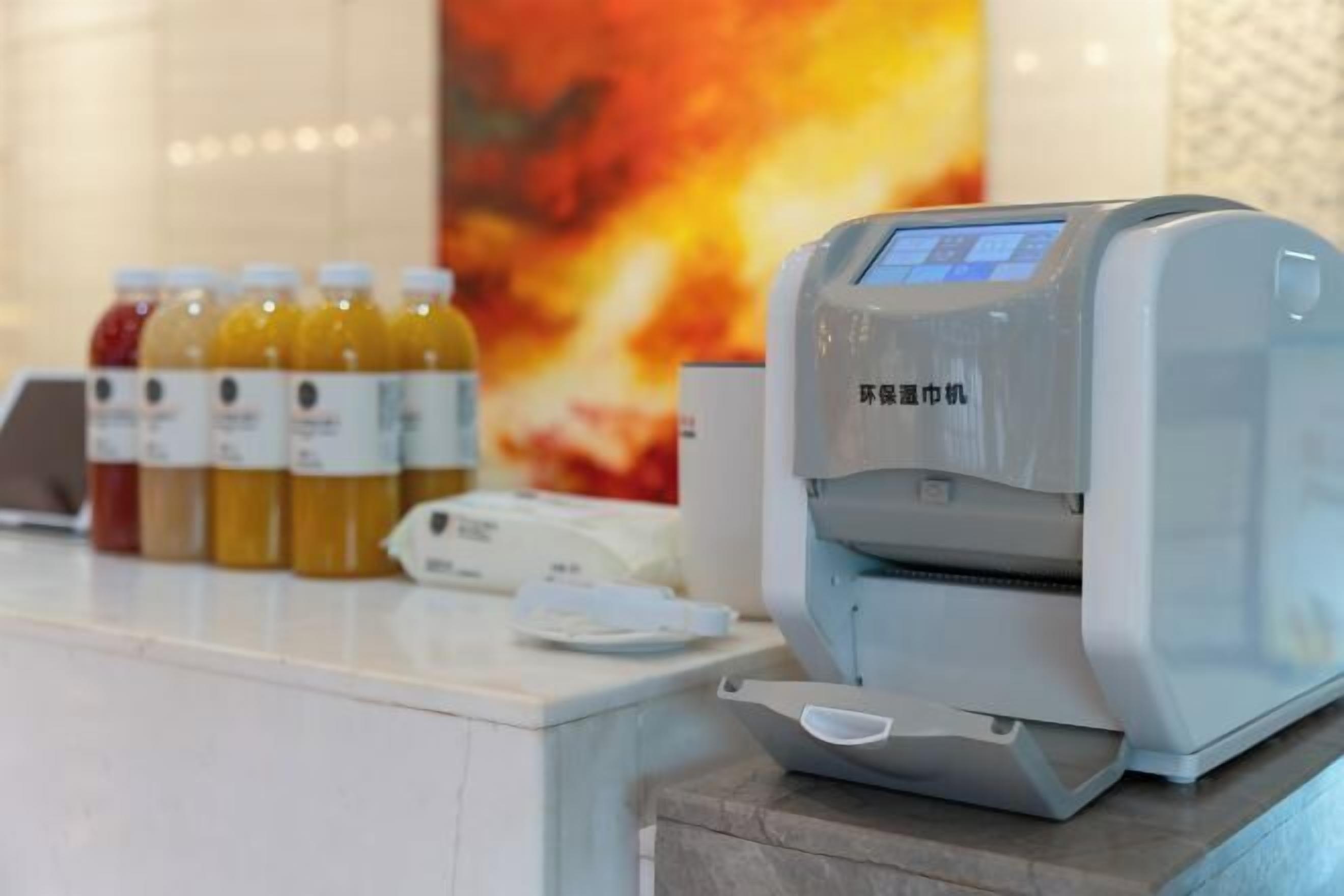 Un dispensador automático de bebidas con pantalla digital, una variedad de bebidas embotelladas y una barra blanca.