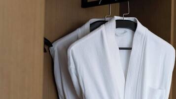 A white robe hanging on a black hanger in a wooden closet.