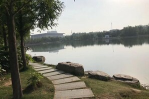 A calm lake with a stone pathway leading to a gazebo. - Hongbao Hotel (Xuchang Caowei Ancient City Pang Donglai Times Square) (Xuchang)
