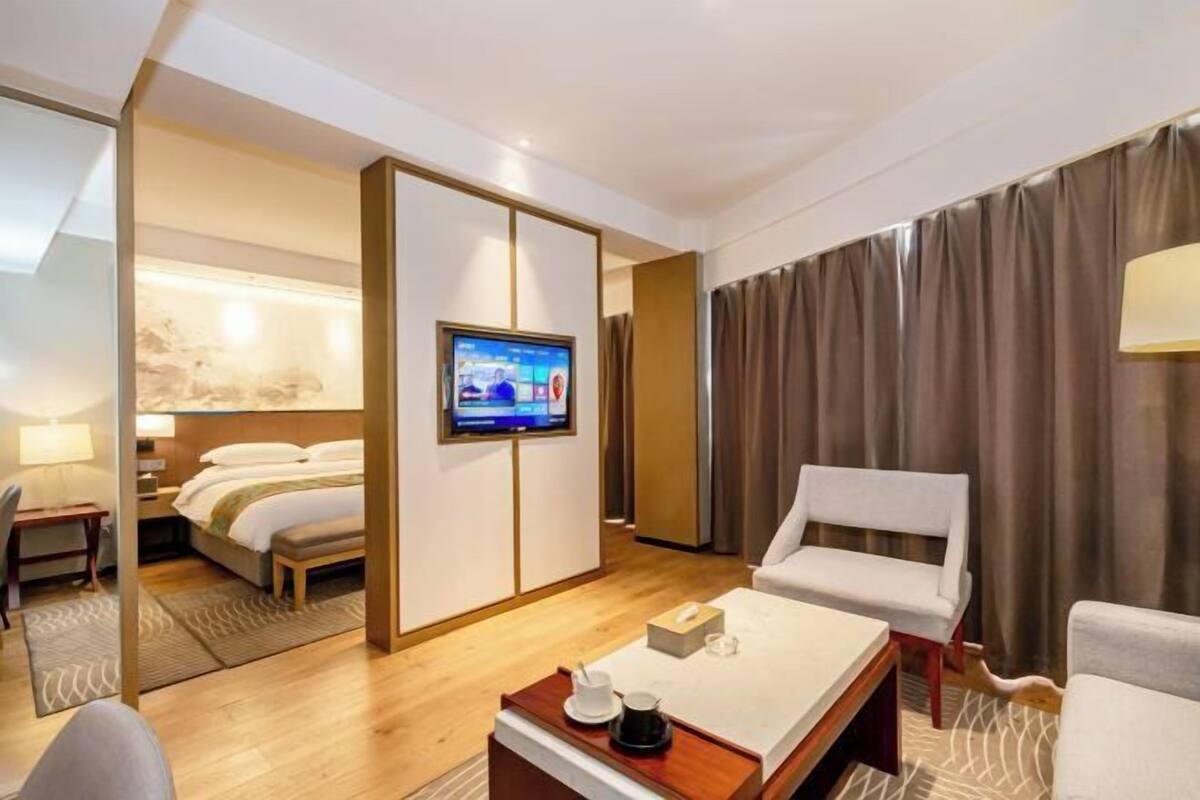 A hotel room with a bed, a TV, a coffee table, and a seating area.