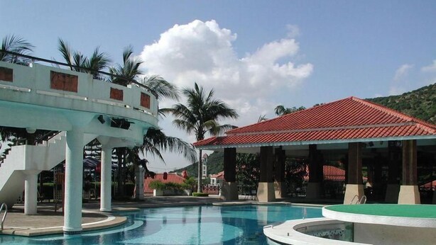 Piscina com estrutura branca e um pavilhão com telhado vermelho.