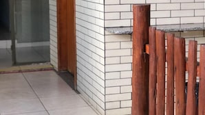 A tiled wall with a framed picture, a wooden door, and a tiled floor. - Hotel Pousada Marista (Goiania)