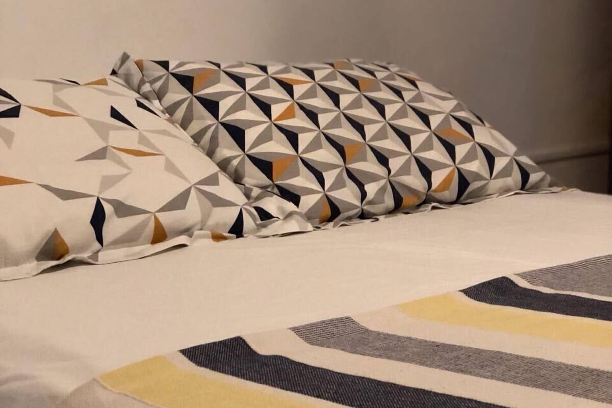 Ein Bett mit einem geometrisch gemusterten Kopfkissen und einer gestreiften Decke.