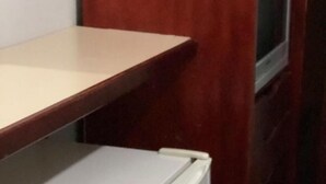 A compact kitchenette with a white refrigerator, a small countertop, and a television on a wooden cabinet. - Hotel Pousada Marista (Goiania)
