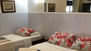 A hotel room with two beds, each with floral and striped bedding. - Hotel Pousada Marista (Goiania)