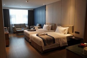Et hotelværelse med en stor seng, en sofa, et sofabord og et skrivebord.