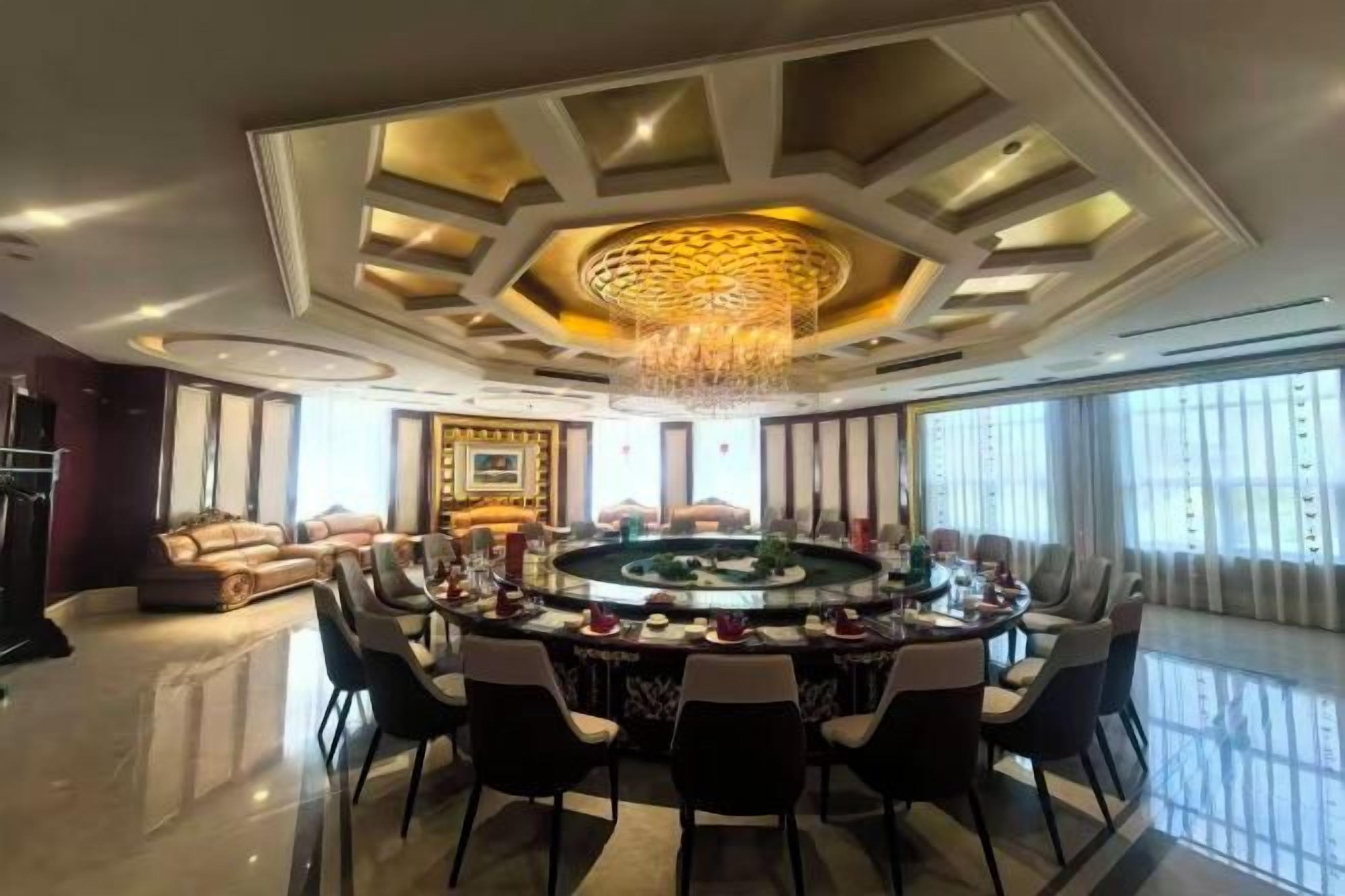 A spacious room with a round bar, a chandelier, and a sofa.