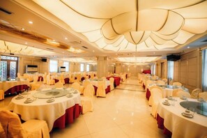 A banquet hall with round tables, chairs, and a stage area. - Fengleyuan Hotel (Zhengzhou)