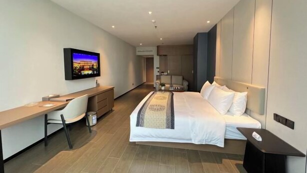 A modern hotel room with a bed, a desk, a chair, a television, and a small table. - Fengleyuan Hotel (Zhengzhou)