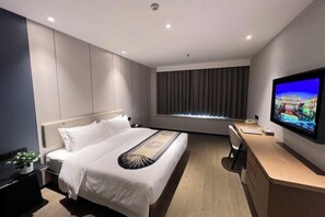 A modern hotel room with a large bed, a desk with a computer, a television, and a window with curtains. - Fengleyuan Hotel (Zhengzhou)