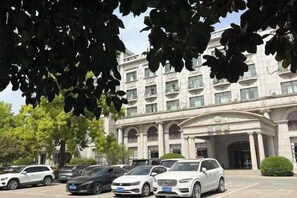 A hotel with a classical facade, a parking lot with several cars, and a well-maintained lawn. - Fengleyuan Hotel (Zhengzhou)