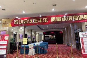 A conference room with a red banner, tables with white tablecloths, and a red carpeted floor. - Fengleyuan Hotel (Zhengzhou)