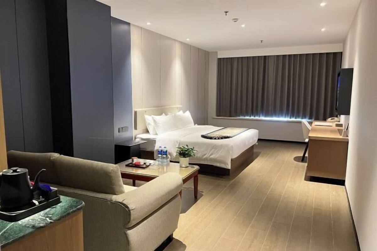 A modern hotel room with a bed, a desk, a chair, a coffee table, and a TV.
