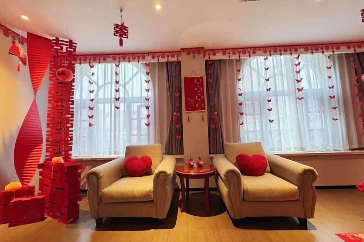 A room with two beige armchairs, a small round table, and a decorative red wall.